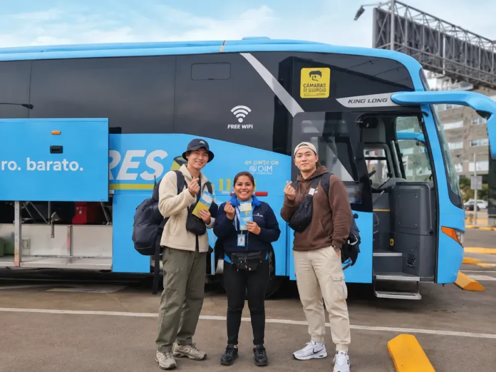Pasajeros junto a guía frente a un bus azul de Airport Express Lima