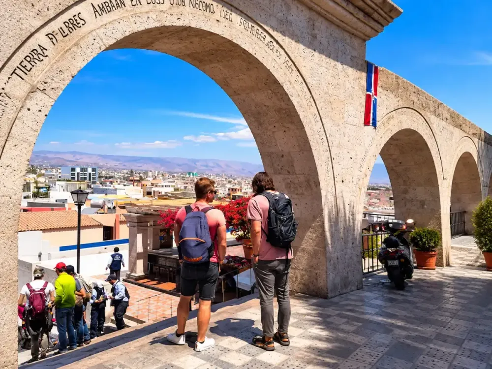 Dos turistas con mochilas miran la ciudad bajo los arcos de Yanahuara