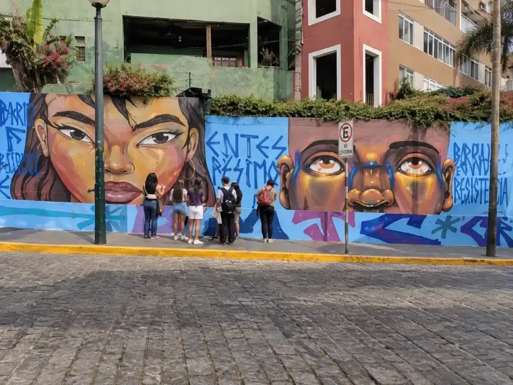 Jóvenes contemplando un gran mural artístico en la Bajada de Baños.