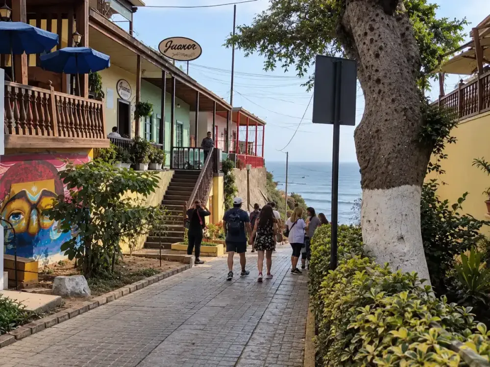 Turistas caminando por el paseo empedrado de la Bajada de Baños en Barranco hacia el mar.