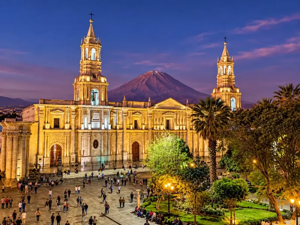 Catedral de Arequipa iluminada de noche con el volcán Misti de fondo al atardecer