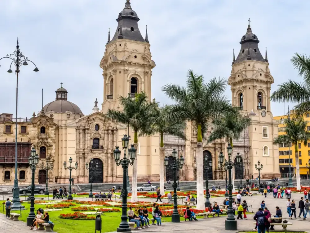 Vista de la Basílica Catedral de Lima desde la Plaza Mayor con palmeras de fondo.