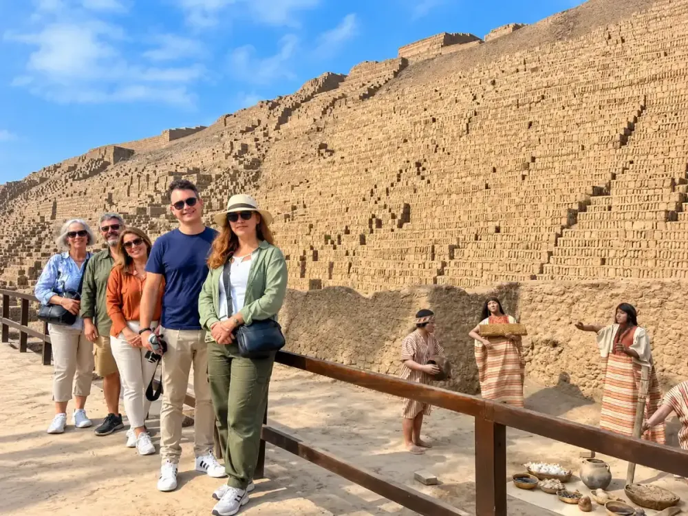 Grupo de turistas posando frente a la gran pirámide de adobe de Huaca Pucllana.