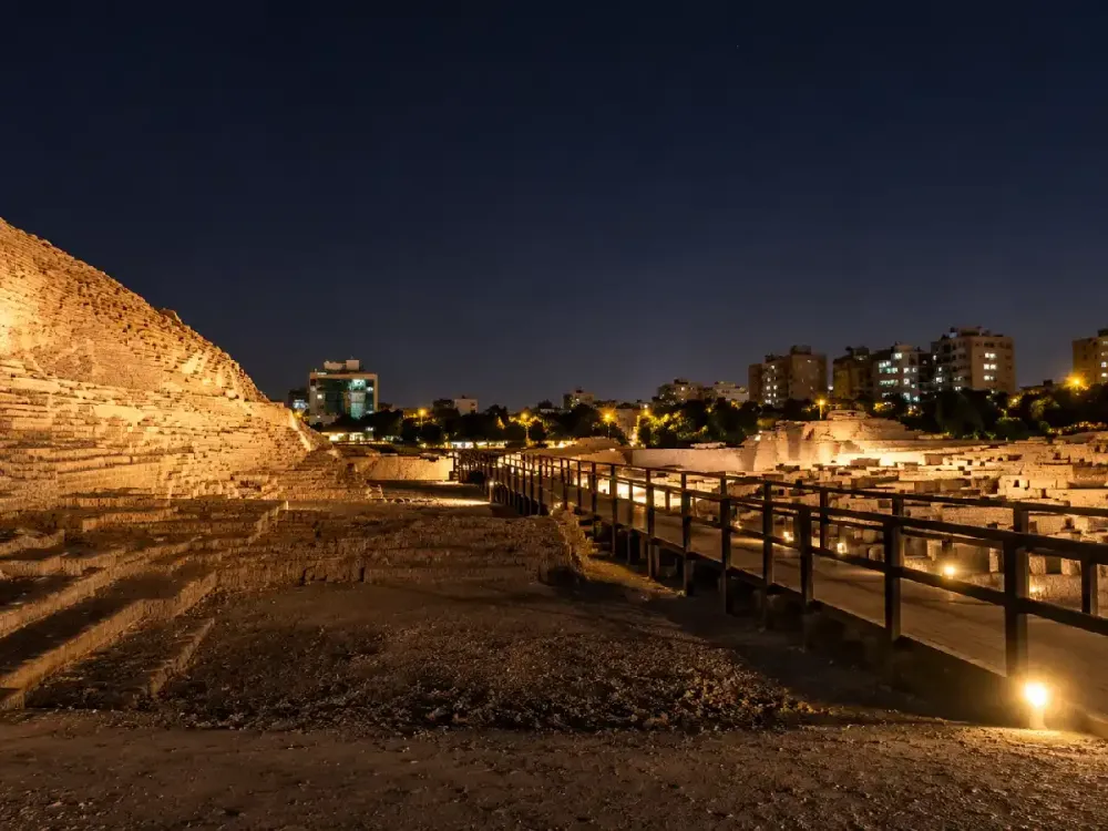 Vista nocturna iluminada de las pasarelas y ruinas en Huaca Pucllana