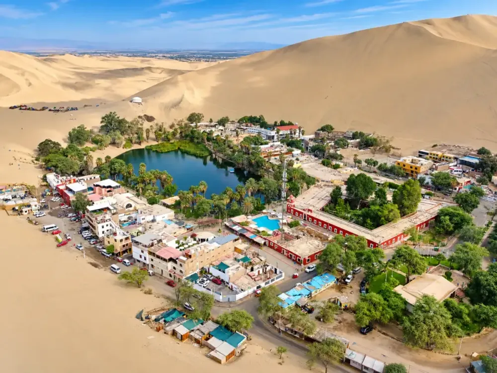 Vista aérea del oasis de Huacachina rodeado de dunas en Ica, Perú.