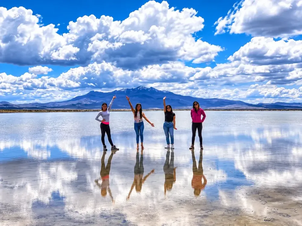Cuatro mujeres saludan reflejadas en el agua de la Laguna de Salinas