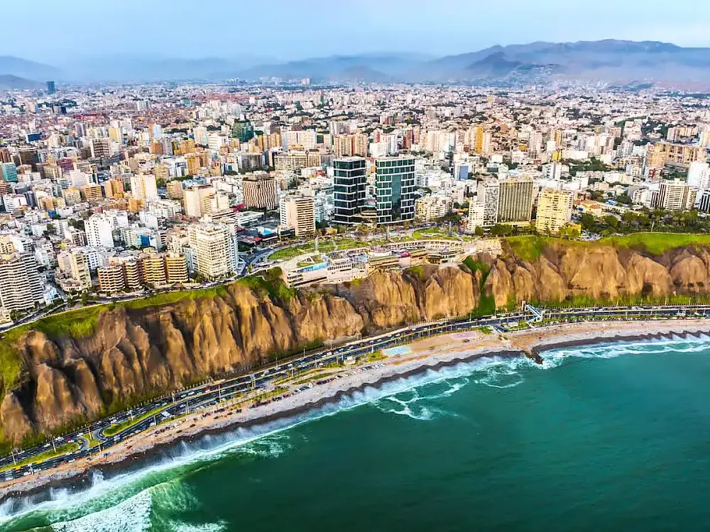 Vista aérea de los acantilados de la Costa Verde en Miraflores, Lima, Perú, mostrando el contraste entre la ciudad moderna y el océano Pacífico.
