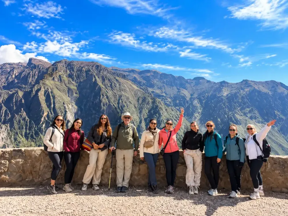 Grupo de turistas posa junto al muro de piedra en el Mirador Cruz del Cóndor