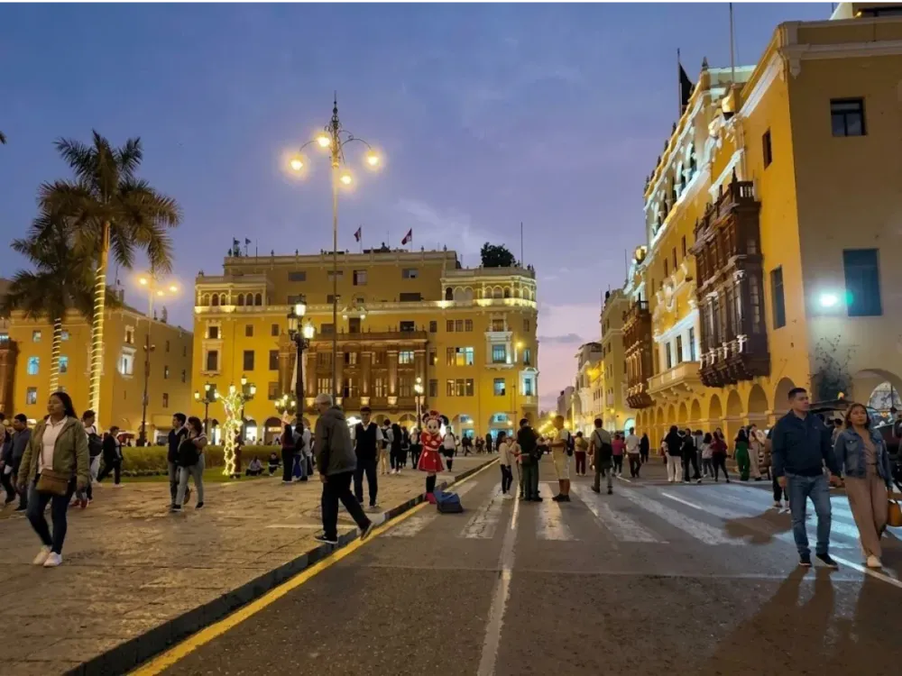 Personas caminando por la Plaza Mayor de Lima durante el atardecer 