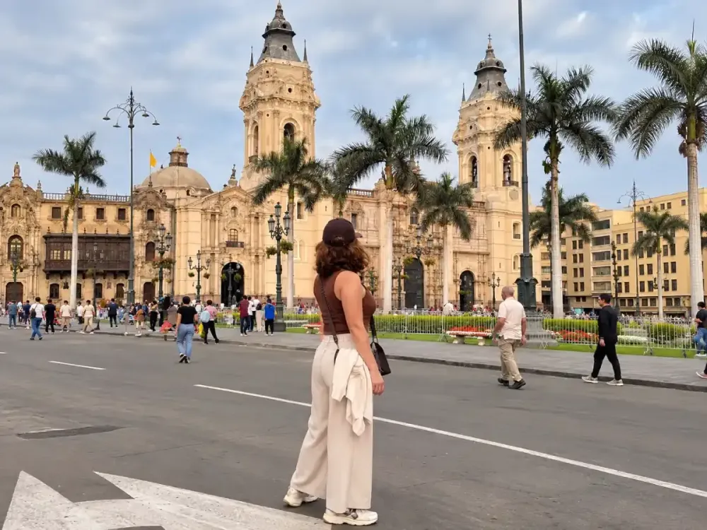 Mujer de espaldas mirando la Catedral de Lima desde la Plaza Mayor de día