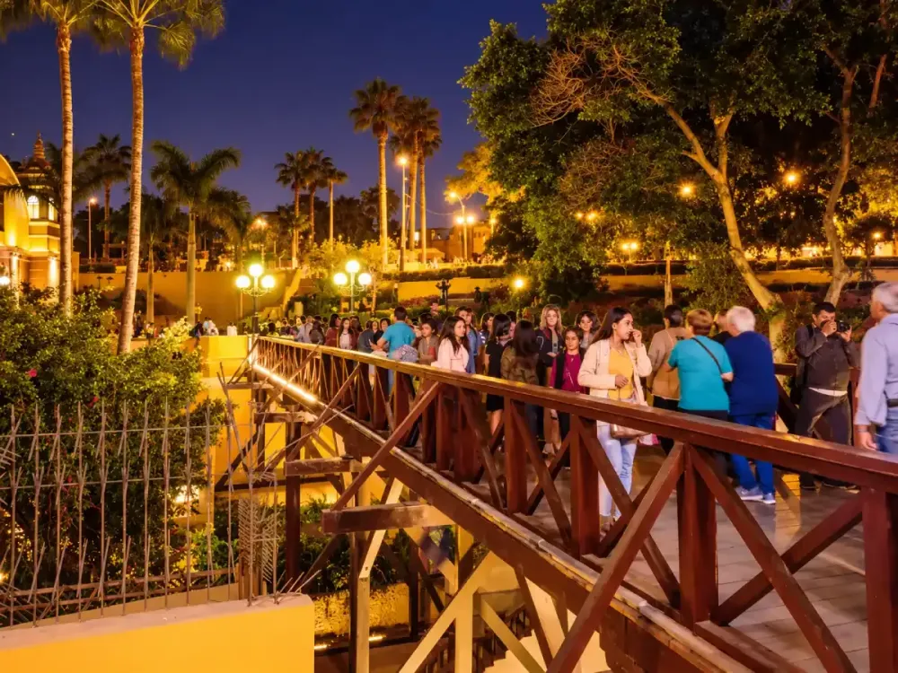 Personas cruzando el iluminado Puente de los Suspiros en Barranco Lima