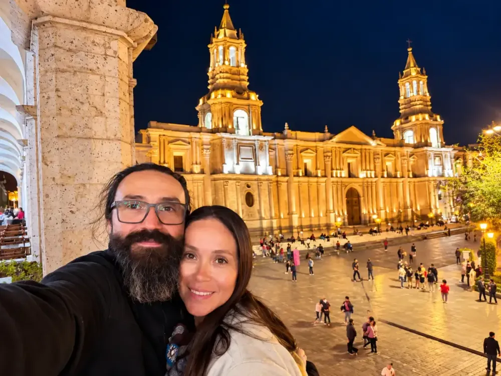 Selfi de una pareja sonriente en la Plaza de Armas de Arequipa de noche