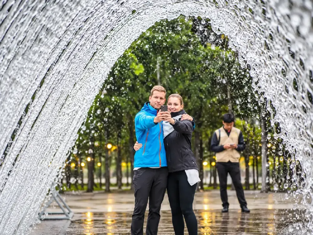 Pareja tomándose una selfie bajo el arco de agua de la Fuente de las Sorpresas.