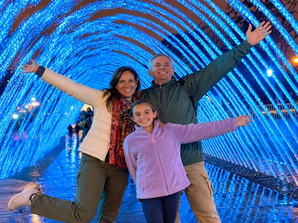 Familia sonriente posa dentro del túnel de agua iluminado de la Fuente de las Tradiciones.