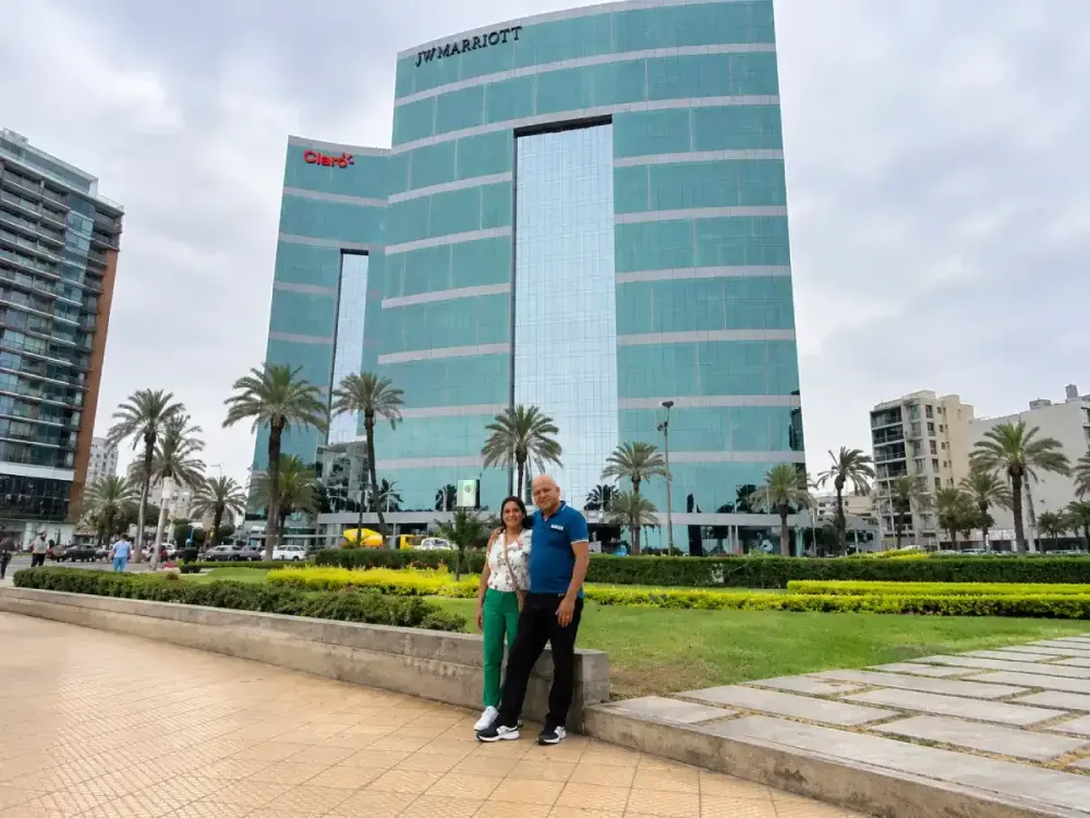 Pareja sonriente posa frente a la gran fachada de vidrio del JW Marriott Lima.