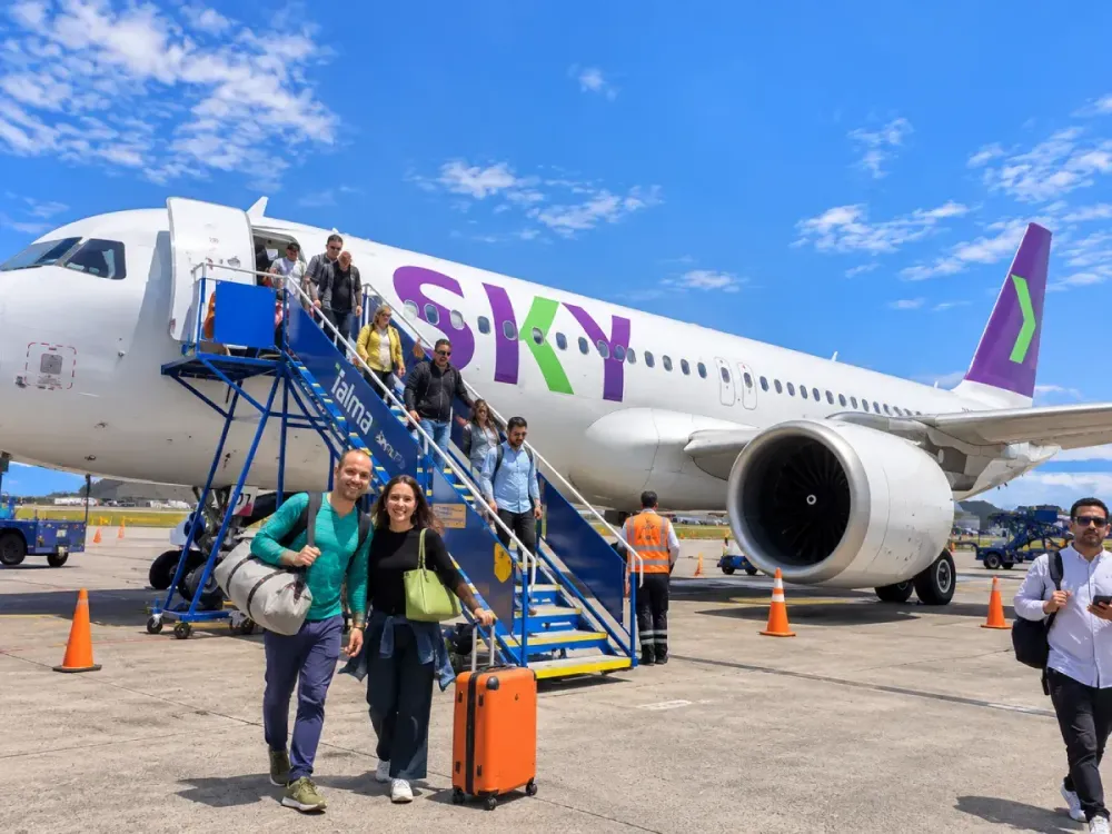 Pasajeros bajando de un avión de Sky Airline en la pista de aterrizaje