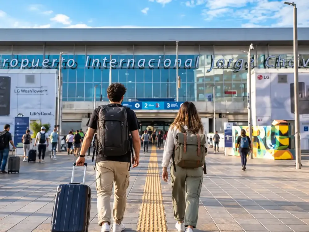 Dos turistas caminando hacia la entrada del Aeropuerto Internacional Jorge Chávez con mochilas y equipaje.