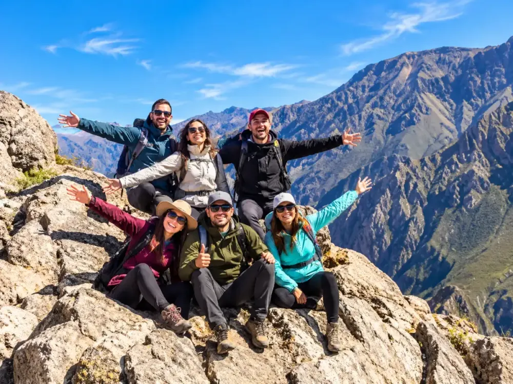 Grupo de excursionistas posa feliz en las rocas frente al Cañón del Colca