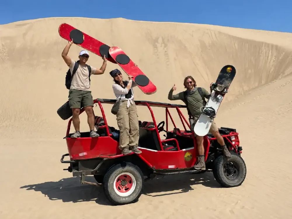 Turistas posando con tablas de sandboard sobre un buggy en las dunas de Huacachina, Ica, Perú.