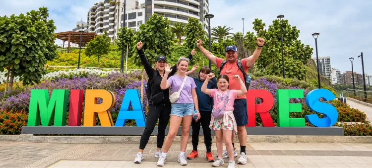 Familia posando alegremente junto al gran letrero colorido de Miraflores.