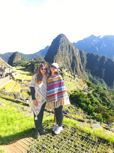 Two travelers visiting Machu Picchu with Huayna Picchu in the background