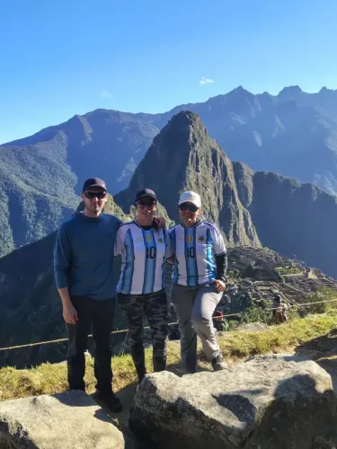 Three travelers at Machu Picchu with Huayna Picchu in the background